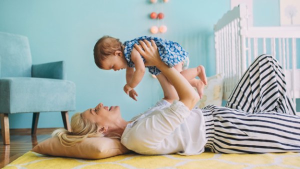 La niñera acostada en el suelo y sosteniendo a una niña