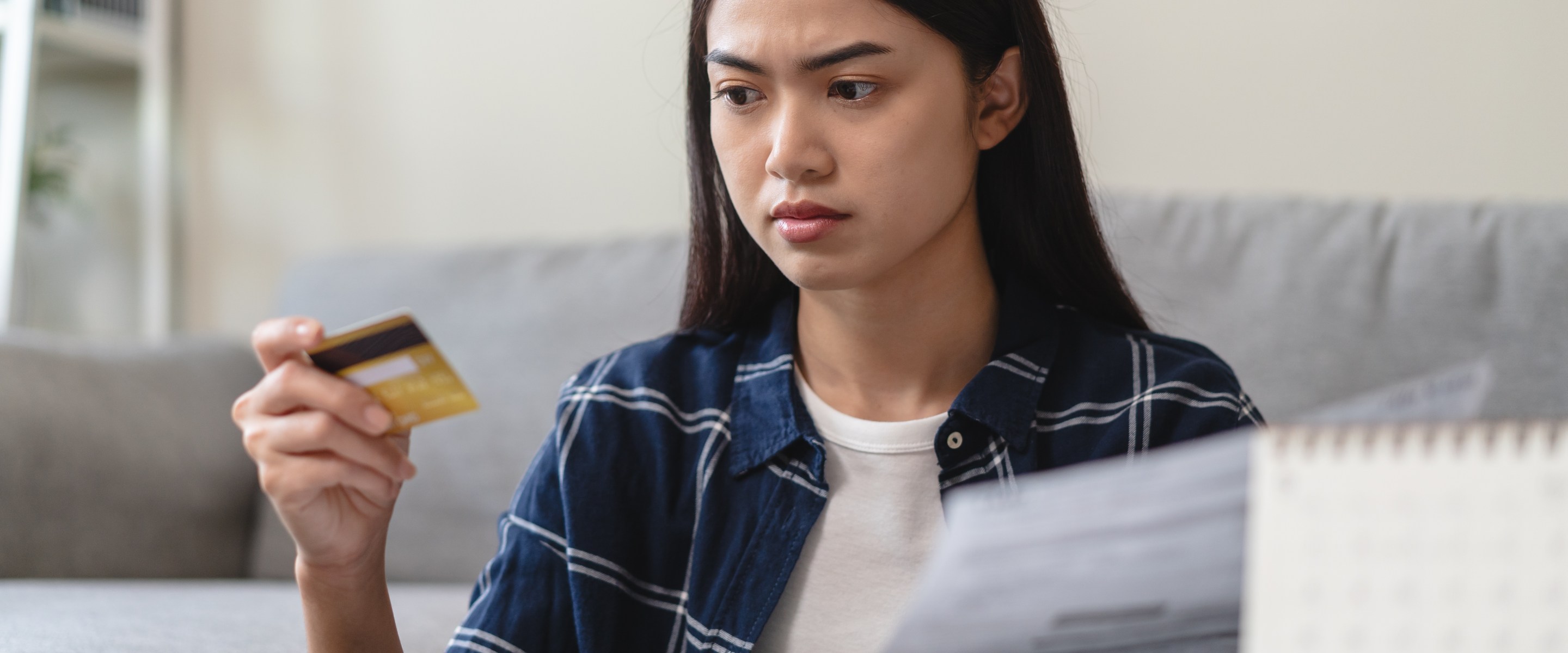 Young Asian woman holding credit card and debt letter