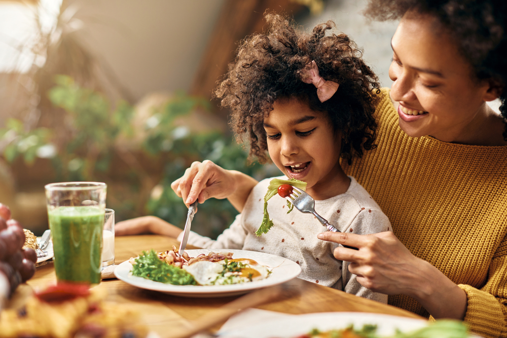 Black mother and daughter eating a healthy meal.