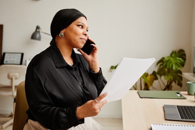 Black business woman holding a stack of documents.