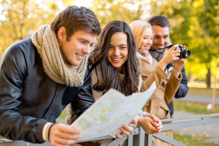 Group of young adults looking at map while traveling.