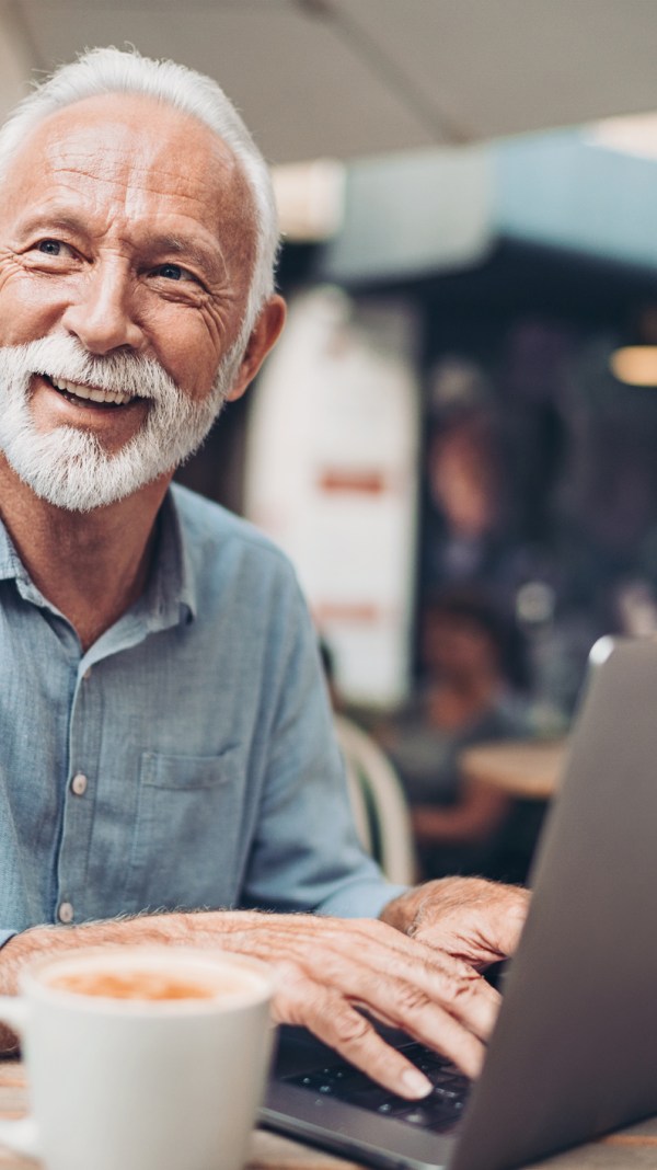 Senior man using laptop to verify his identity.