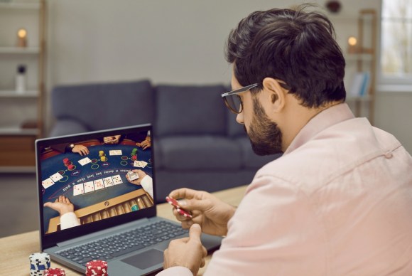 Young bearded man playing poker online.