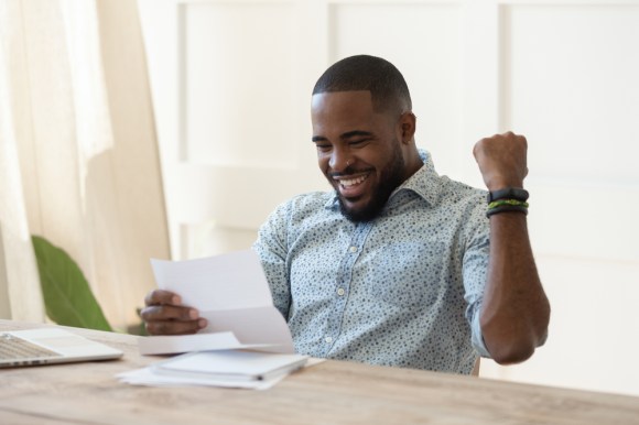 Young Black man getting good news when opening mail.