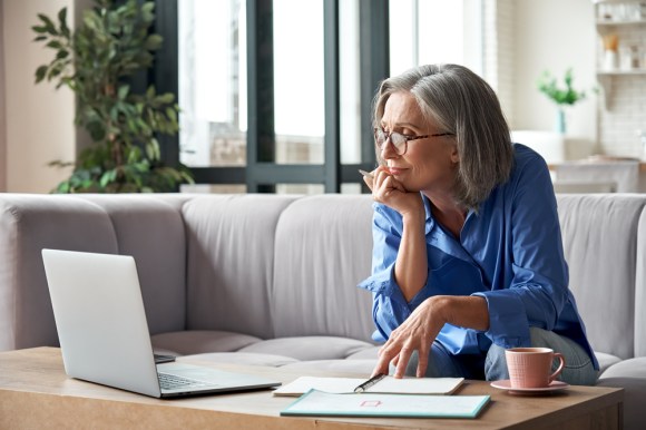 Senior woman sitting on the couch and looking at computer.