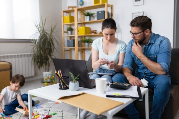 Couple figuring out their taxes together with their child in the background.