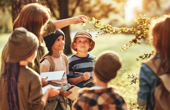 Kids learn about plants with a camp counselor guiding them.