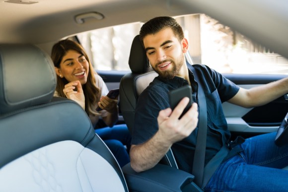 Rideshare driver showing a passenger details on his phone.