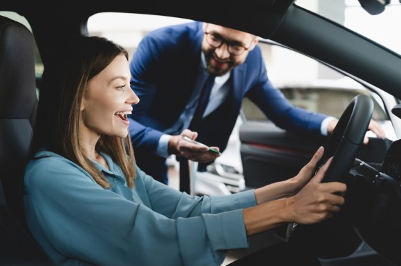 Woman sitting in a car while talking to a car dealer.