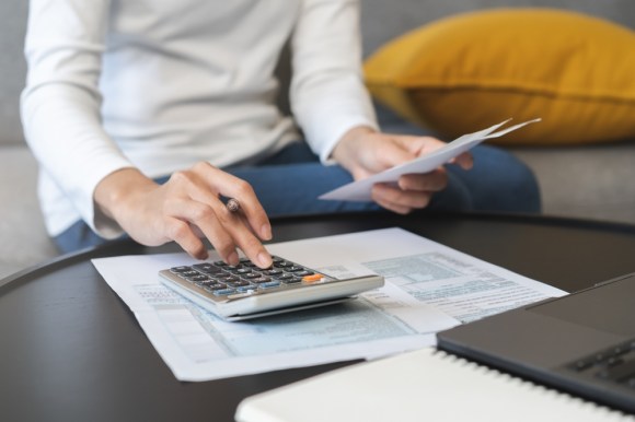 Close-up of a woman sitting on a couch doing her taxes.