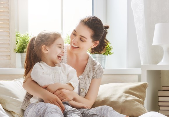 Single woman with a child on her lap sitting on the bed.