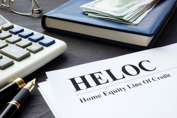 Close-up of HELOC loan documentation, pens, and calculator on desk.