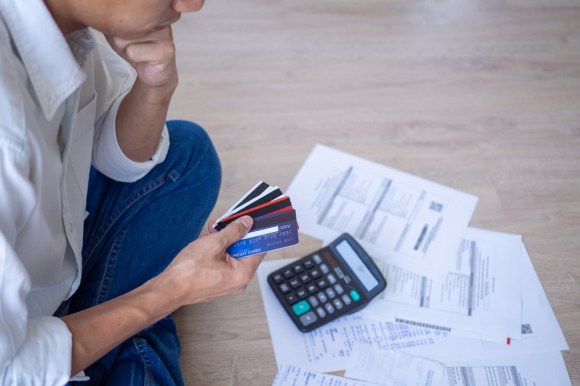 Man looking at credit cards with bills and a calculator in front of him.