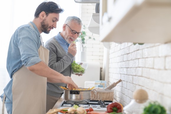 Older man and his adult son cooking dinner.