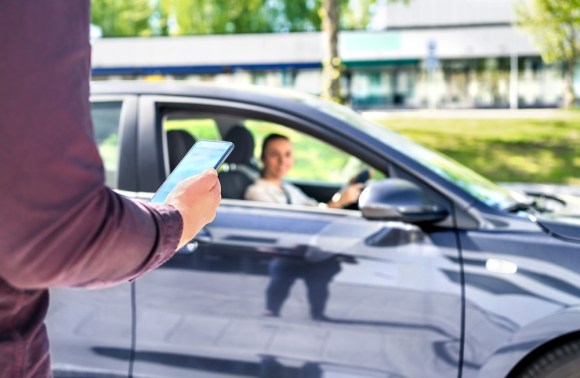 Person holding phone and approaching rideshare driver.