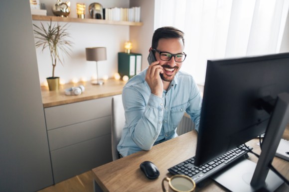 Man speaking on phone while working in home office.