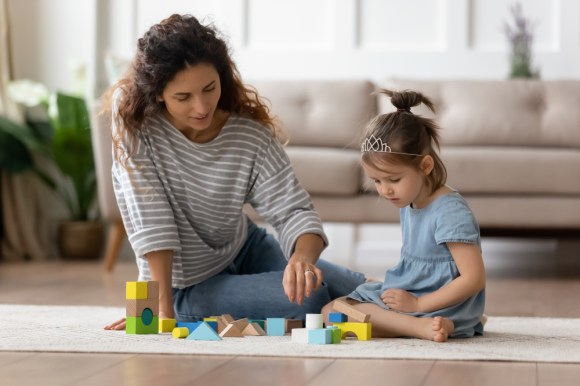 Babysitter playing with blocks with a child.