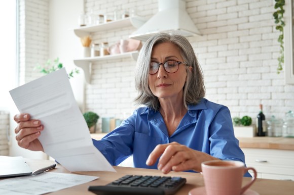 Senior woman using a calculator and reading a document.