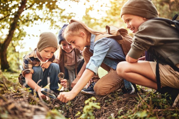 Kids in hiking gear looking at plants.