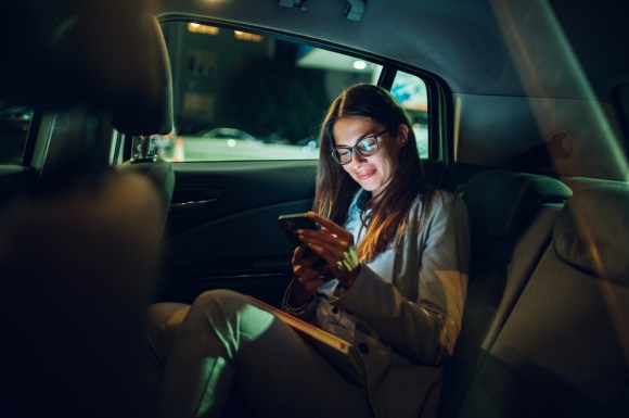 Businesswoman using her phone while riding in the backseat of a car.