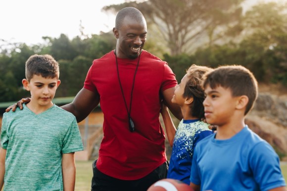 Volunteer coach smiling with kids.