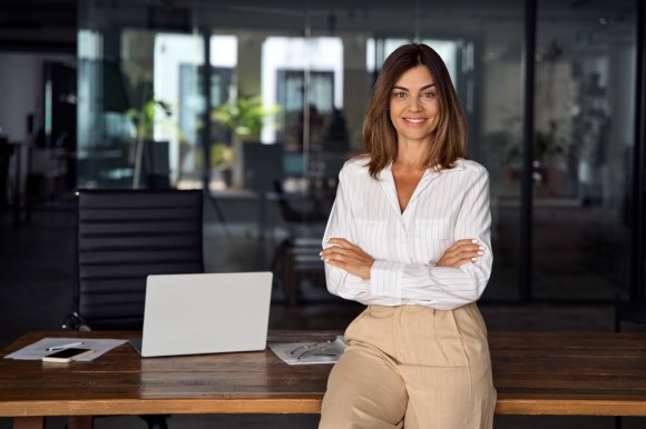 Well-dressed businesswoman leaning on a desk.