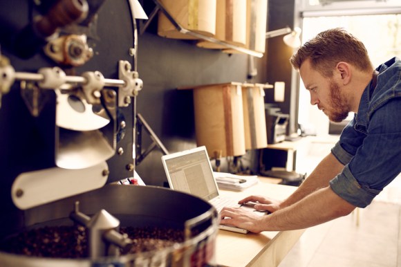 Coffee shop owner working on laptop.