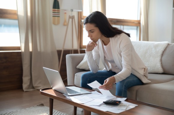 Woman reviewing receipts while looking at her laptop.